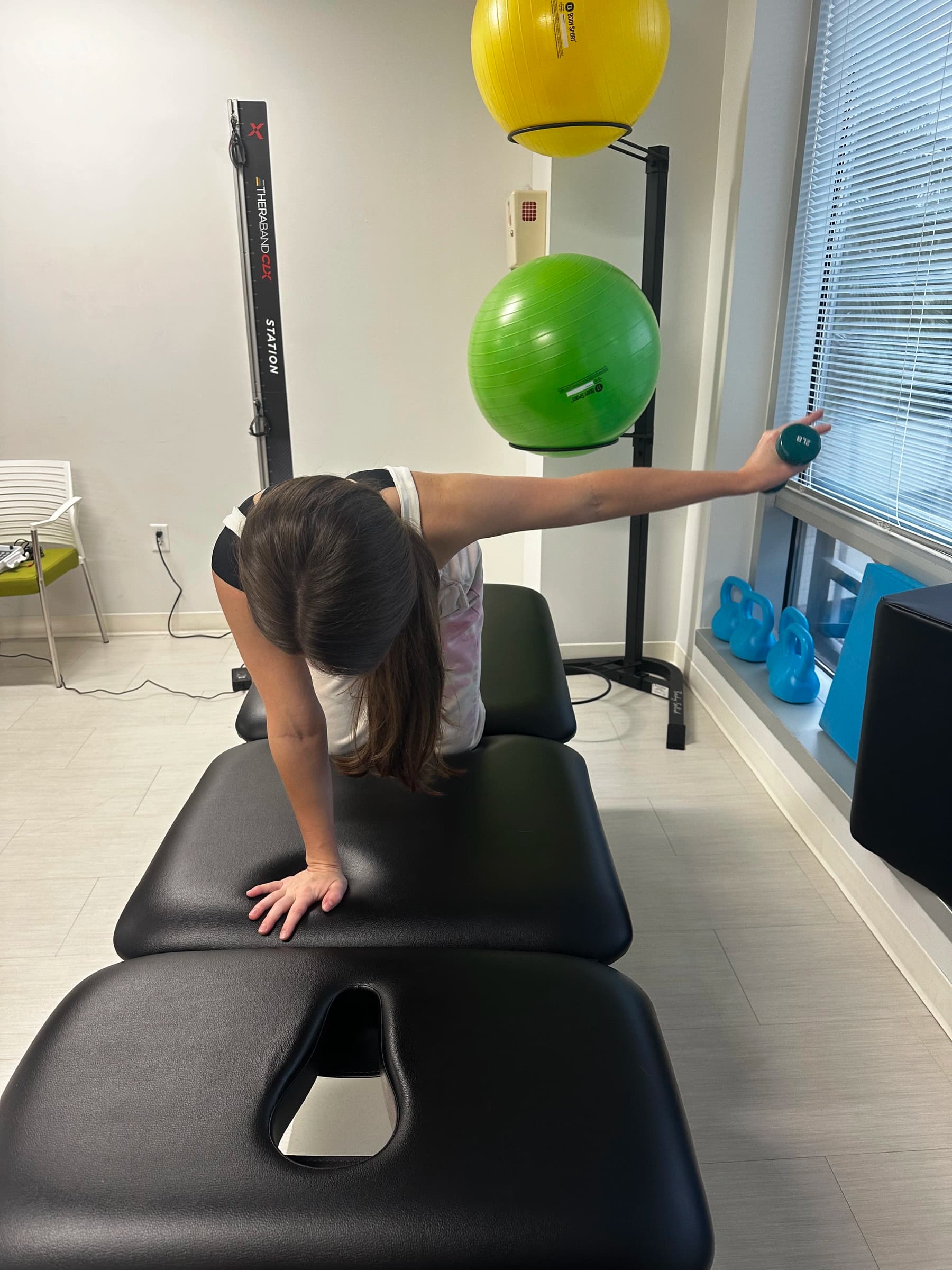 Client performing an overhead reach exercise in the BodyWRX treatment room.