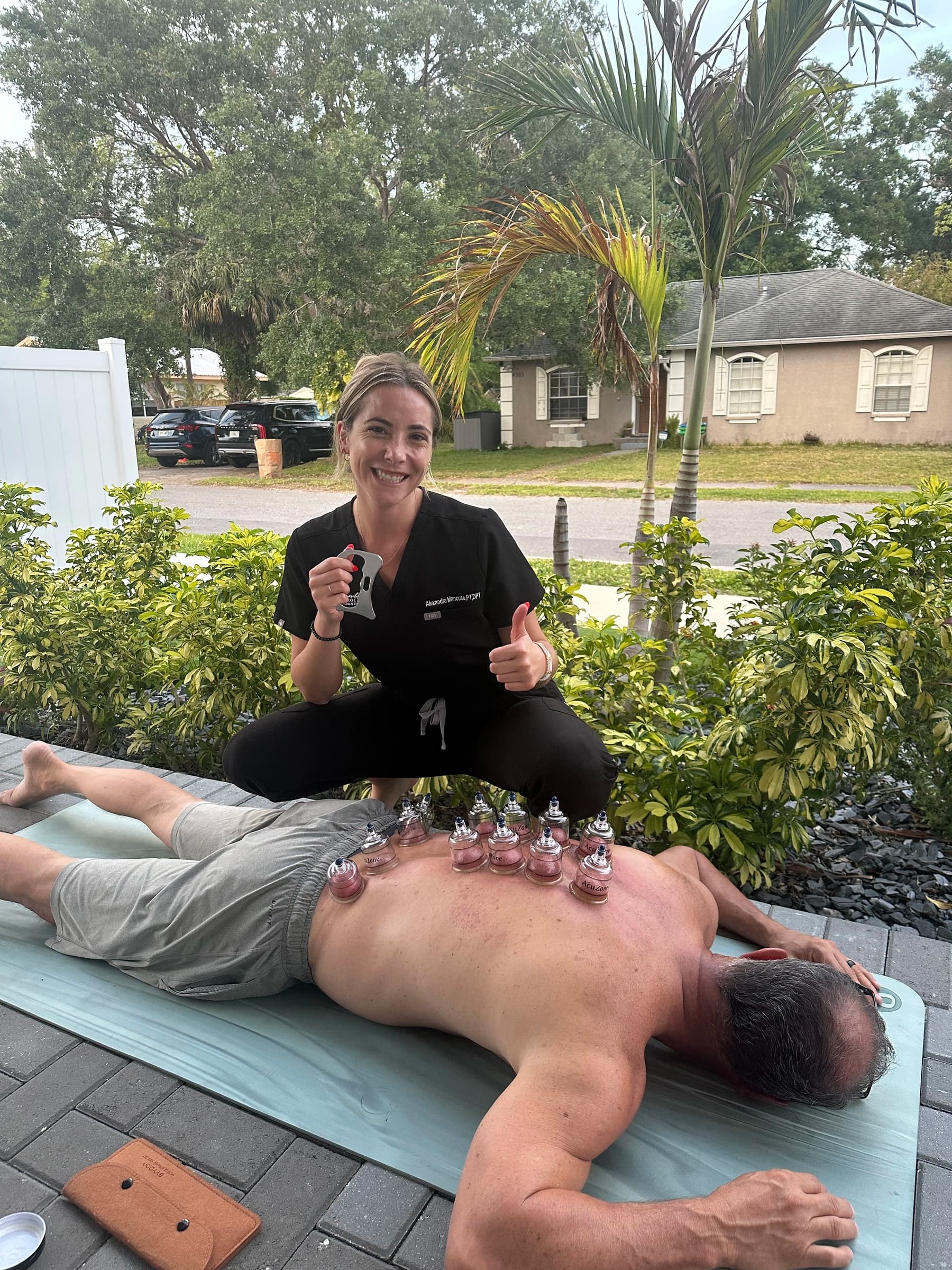 Dr. Mancuso performing cupping therapy on a client's back in an outdoor setting.